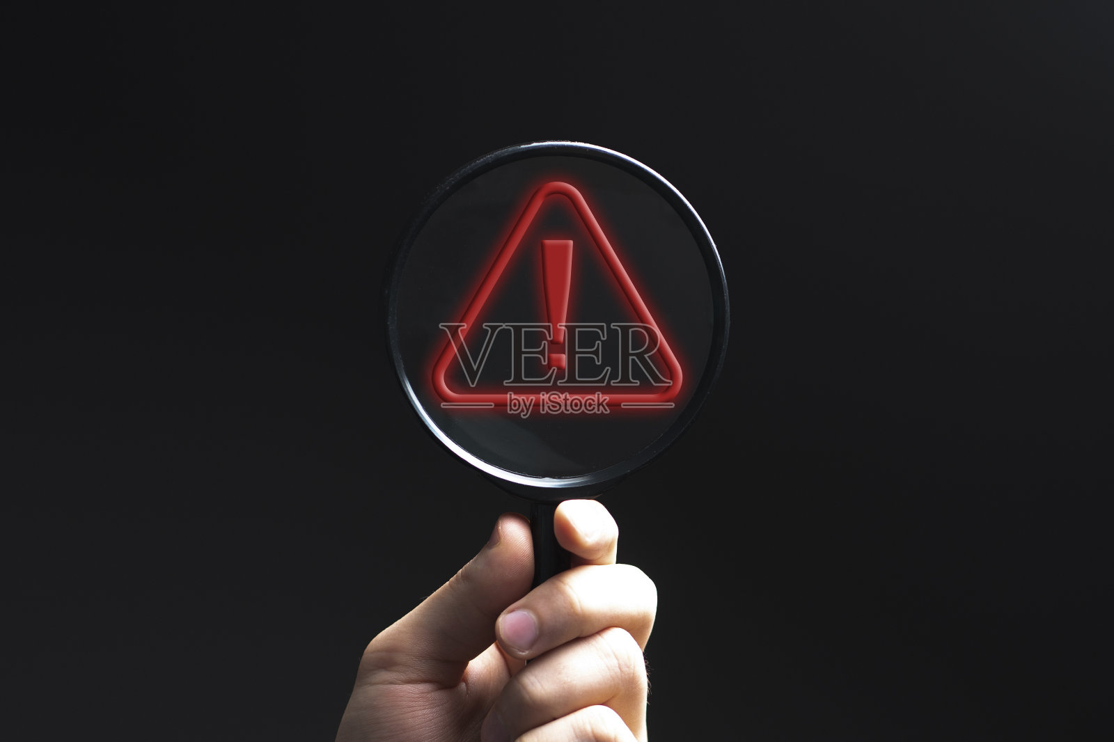 手握放大镜中的红色感叹号，表示警惕照片摄影图片