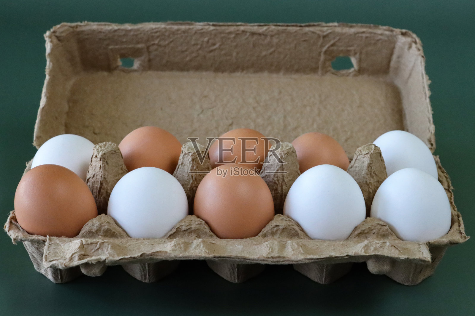 图片打开，棕色纸箱的鸡蛋，混合颜色的鸡蛋，十个白色和棕色的壳，绿色背景，重点在前景照片摄影图片