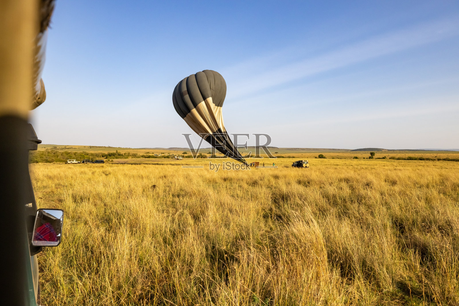 在肯尼亚，泄气的热气球坠落在草地上照片摄影图片