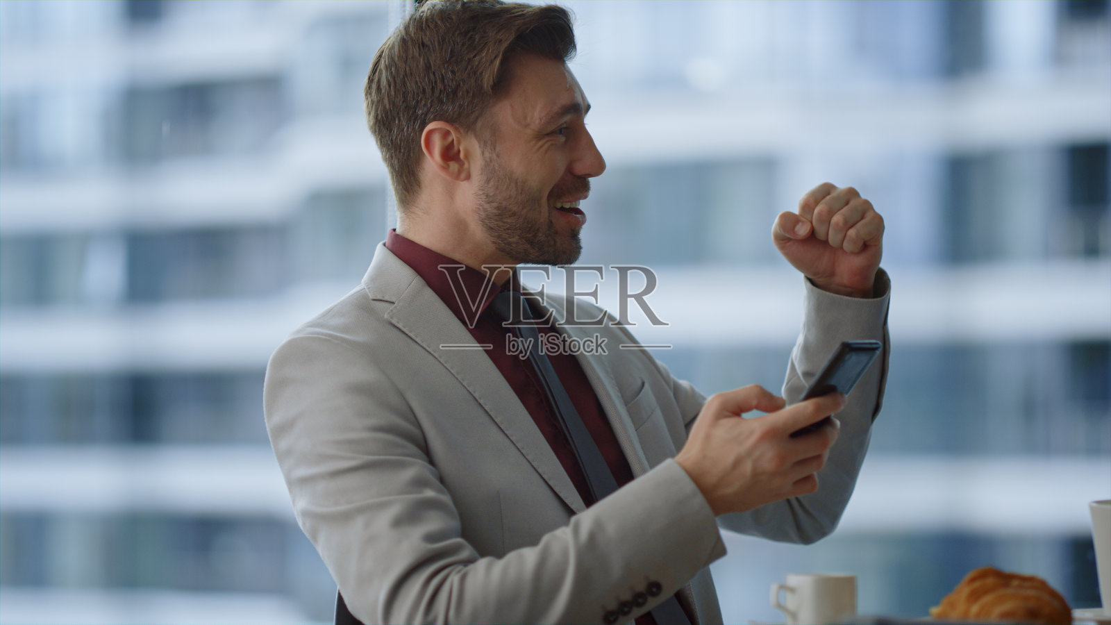 专业人士在咖啡馆办公室用手机阅读好消息庆祝胜利。照片摄影图片