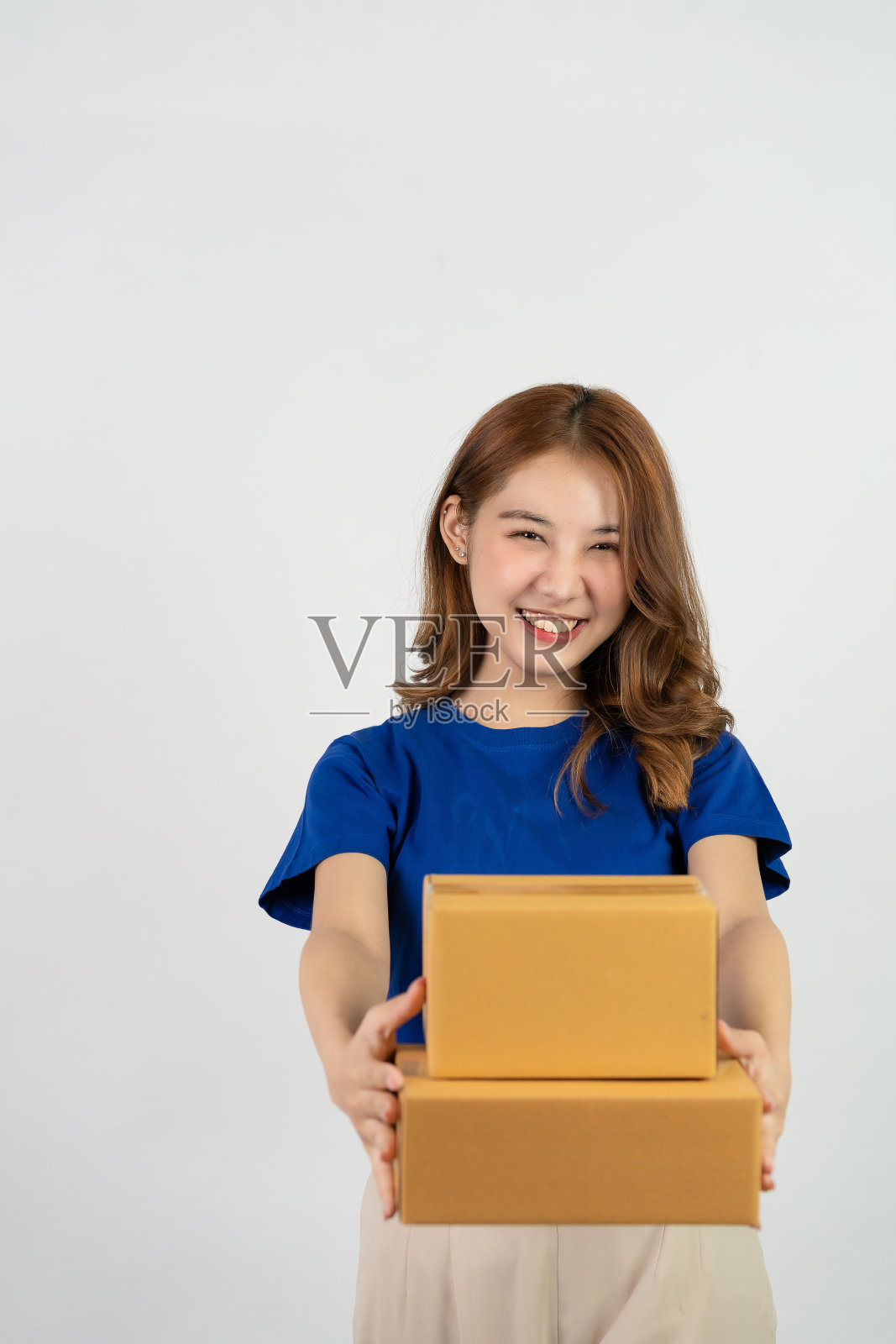 亚洲妇女微笑着快乐地拿着白色背景上孤立的包裹盒子，在网上快递购物。中小企业经营理念。照片摄影图片