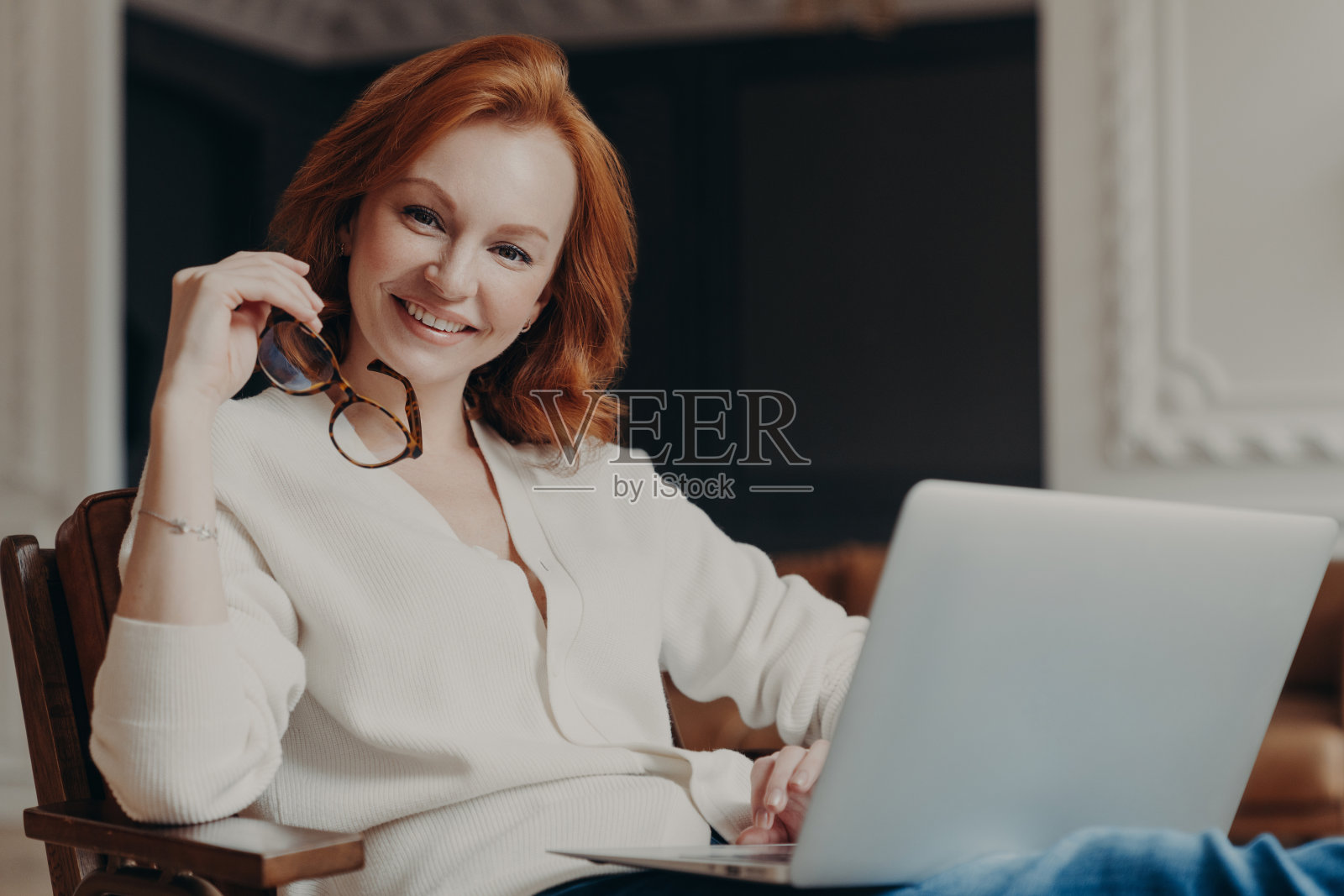 开朗满意的女子在室内拍摄远程工作，忙于远程工作，开始工作前积极地看着相机，使用现代笔记本电脑和无线互联网，浏览信息照片摄影图片