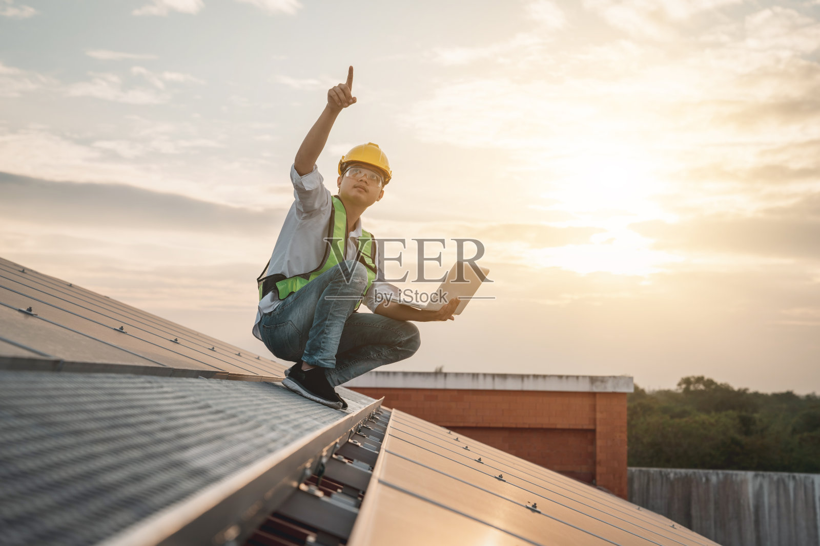 服务工程师检查屋顶上的太阳能电池是否有损坏部分。工程师安装太阳能电池板。清洁能源概念。照片摄影图片
