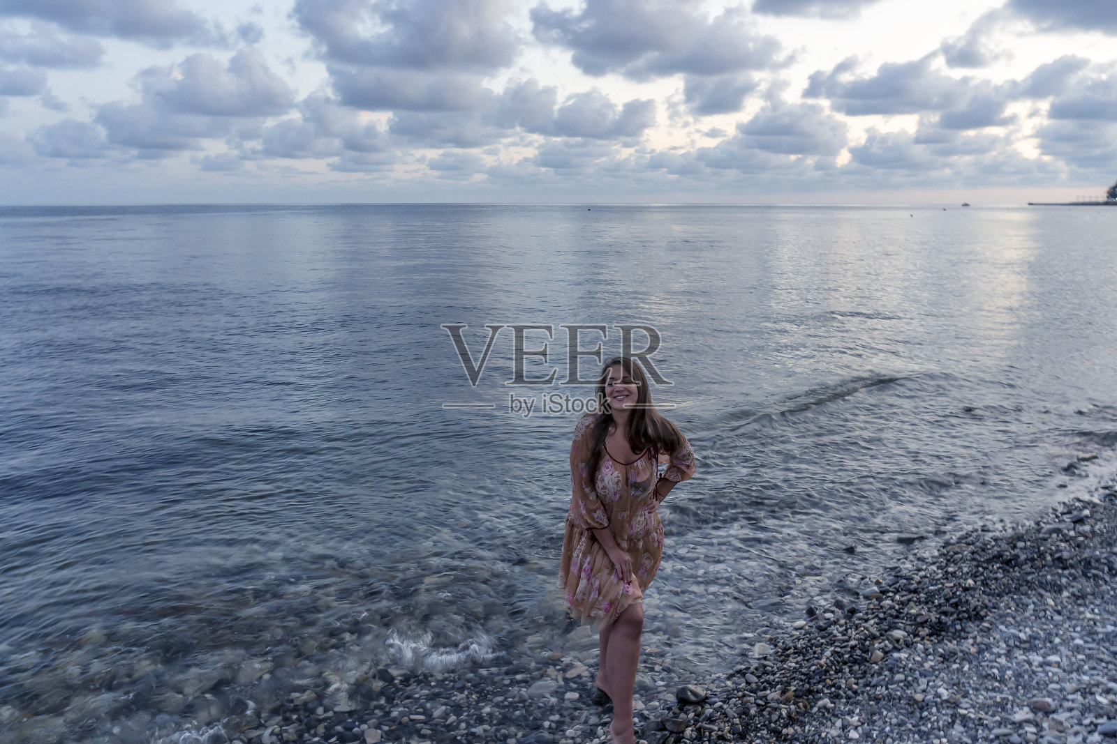 海边夕阳下的年轻女子照片摄影图片