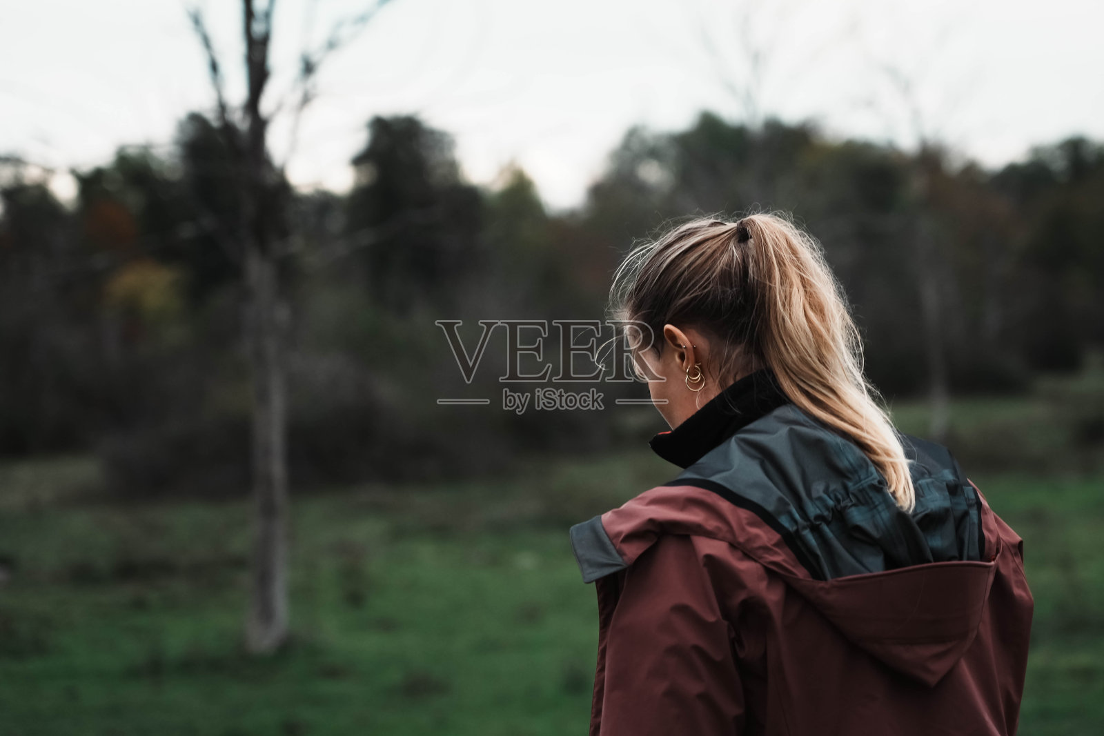 金发女孩走在空旷的草地上。照片摄影图片
