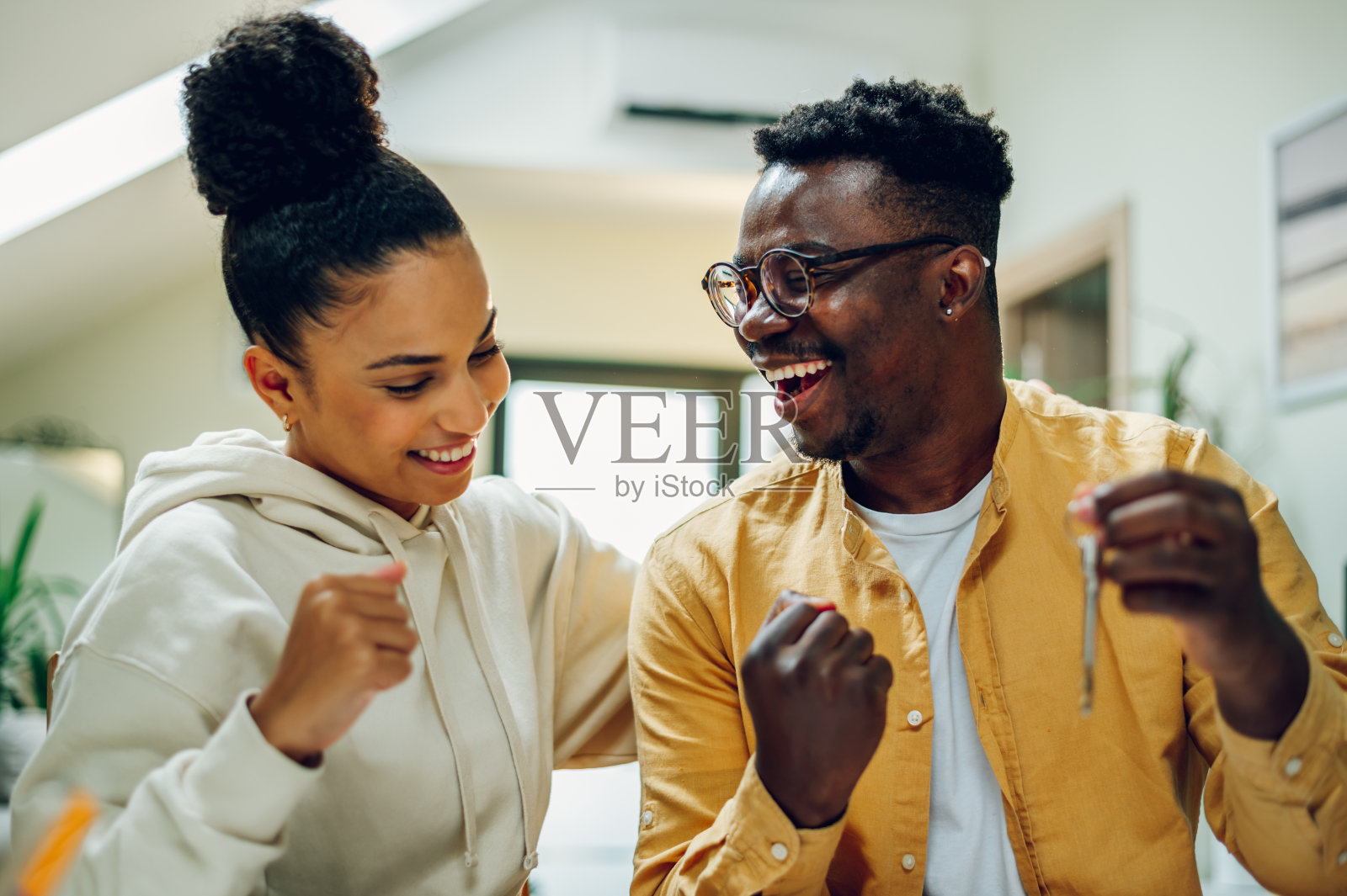 不同的夫妇坐在家庭办公室里，打开他们新家的钥匙照片摄影图片