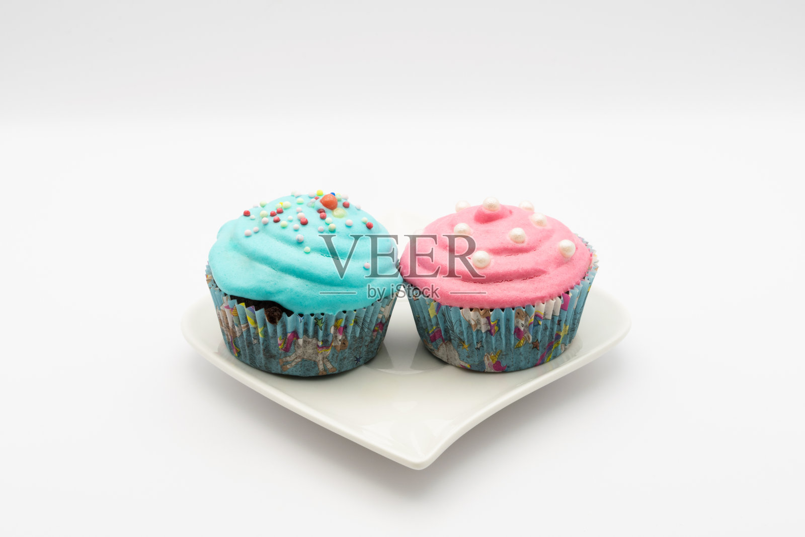 绿松石和粉色纸杯蛋糕放在白色背景的小盘子里照片摄影图片