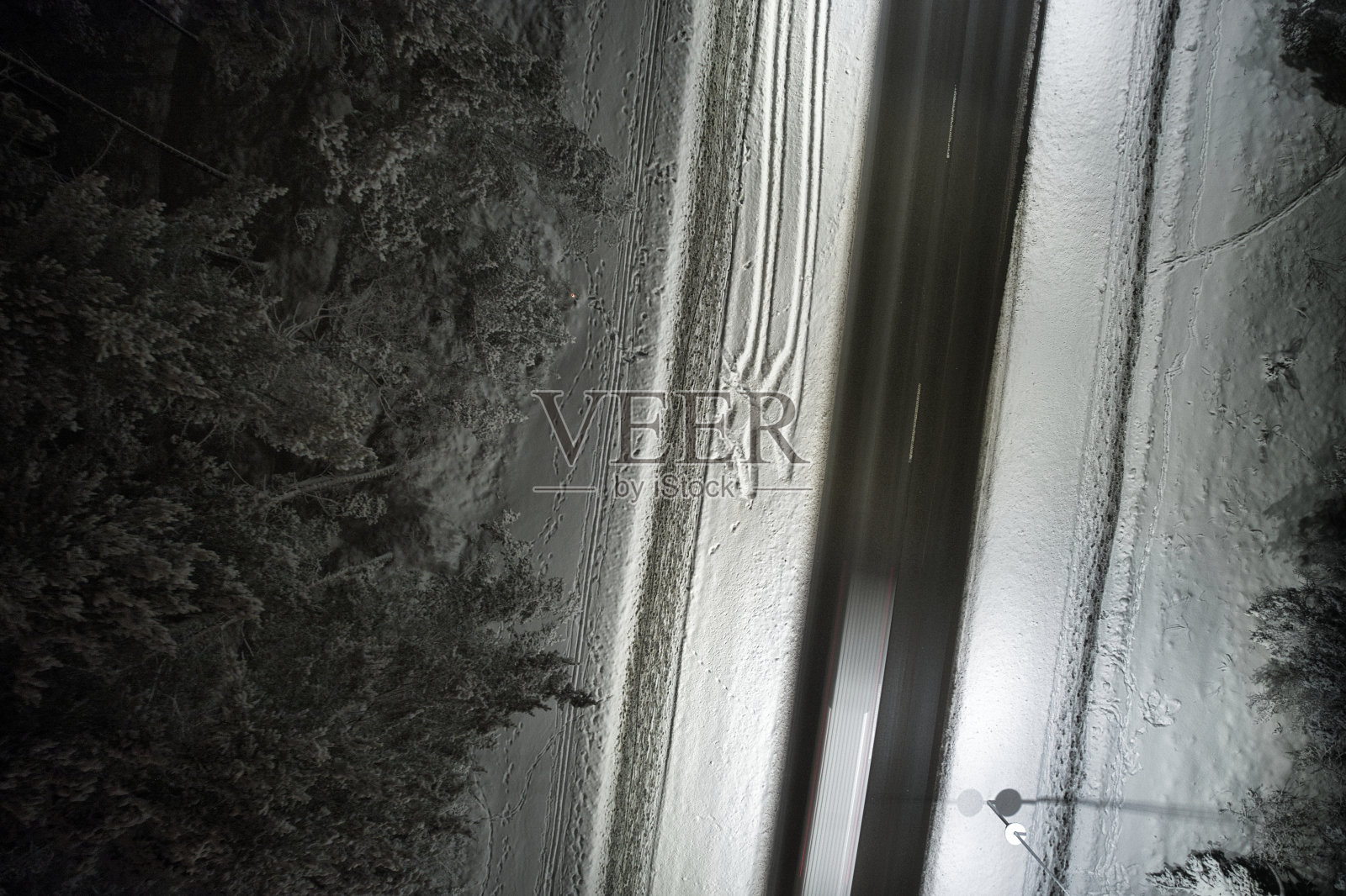 无人机拍摄的冬季道路在夜间蜿蜒穿过积雪覆盖的森林在山上照片摄影图片