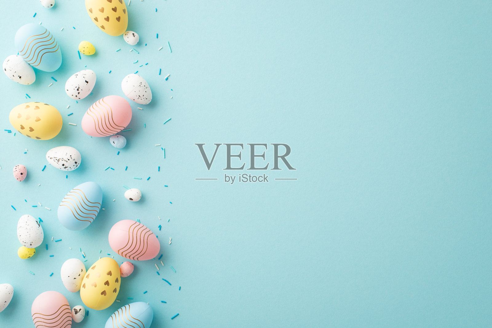 顶部视图照片的黄色，粉红色，蓝色，白色复活节彩蛋和洒在孤立的粉彩蓝色背景与空白照片摄影图片