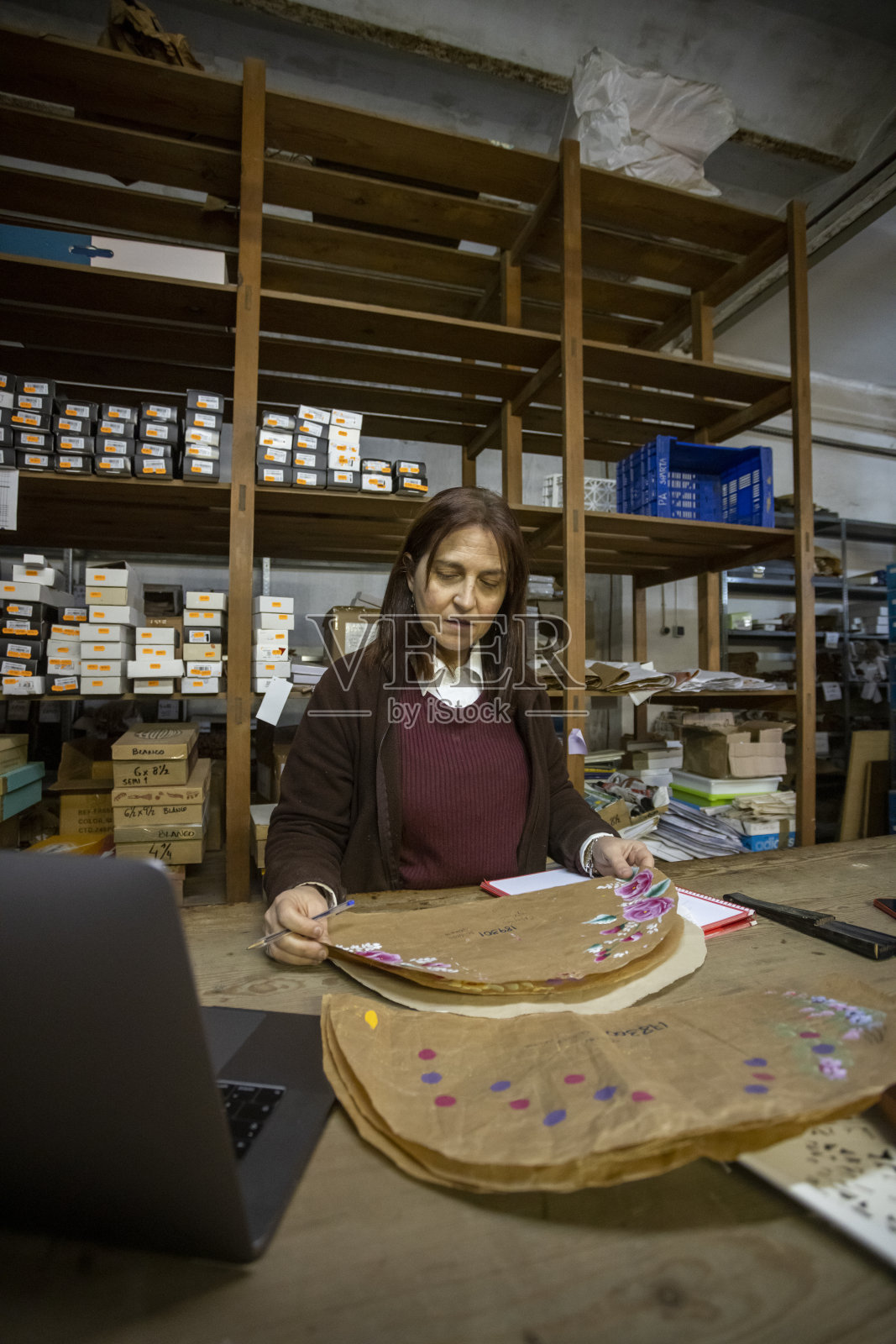 垂直拍摄的一个西班牙女人看着手工风扇设计在车间照片摄影图片