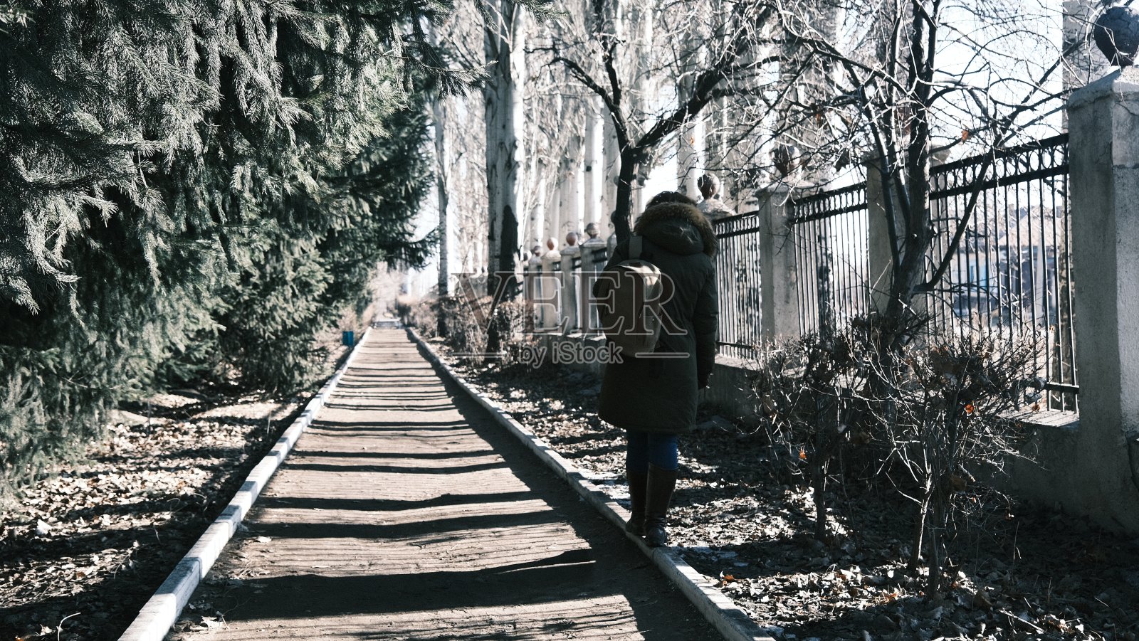 冬末，一位女士走在公园的人行道上照片摄影图片
