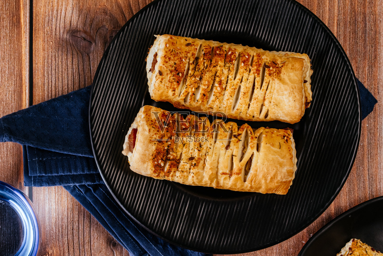 在木制工作台上的黑色盘子里装着面团的香肠照片摄影图片