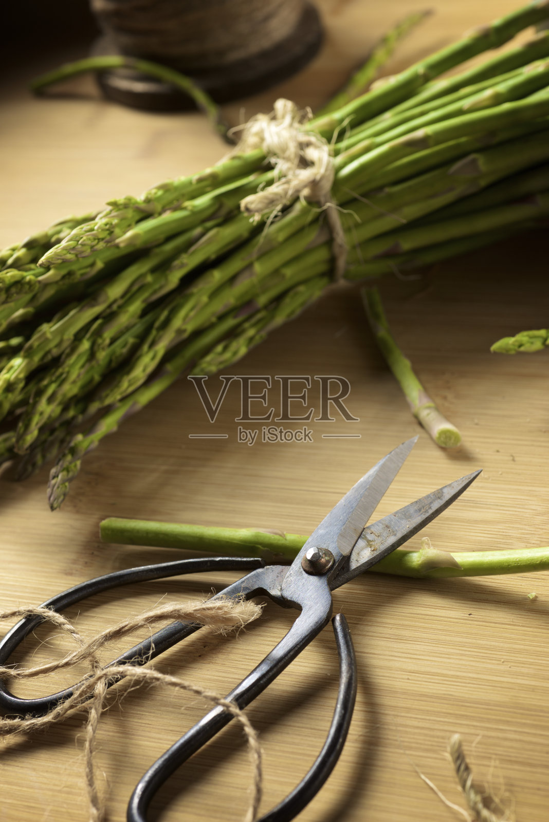 一束野生芦笋，用绳子系好，放在竹桌上照片摄影图片