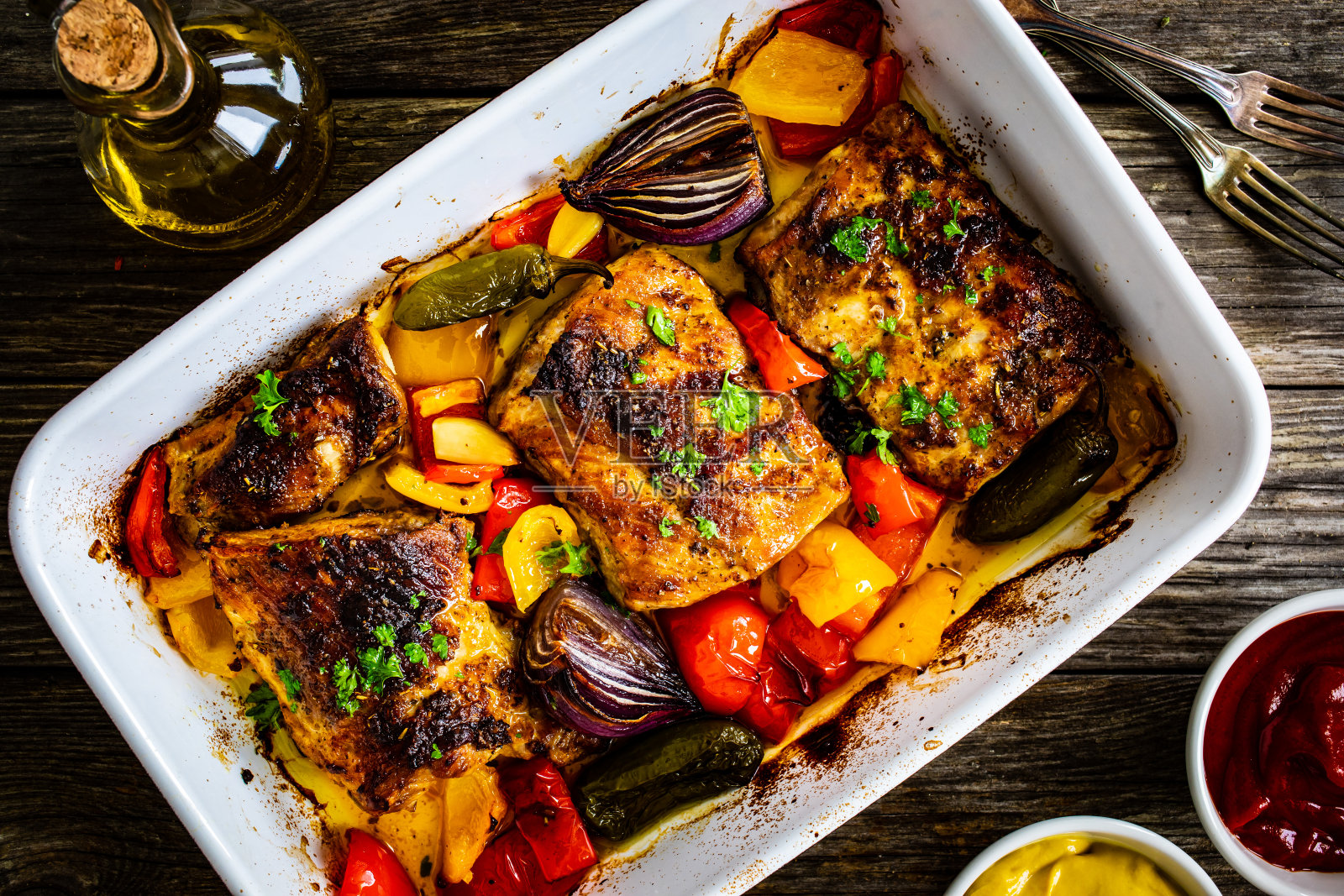 美味的烤排骨配洋葱、彩椒和大蒜，放在木桌上的煎锅里照片摄影图片