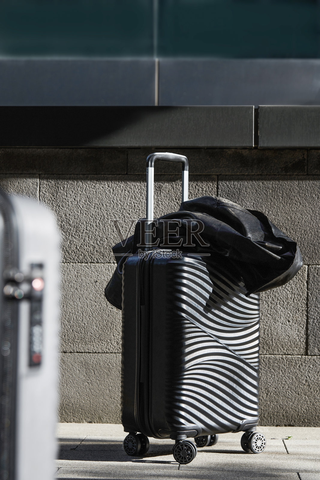 阳光明媚的街道上的黑色行李箱照片摄影图片