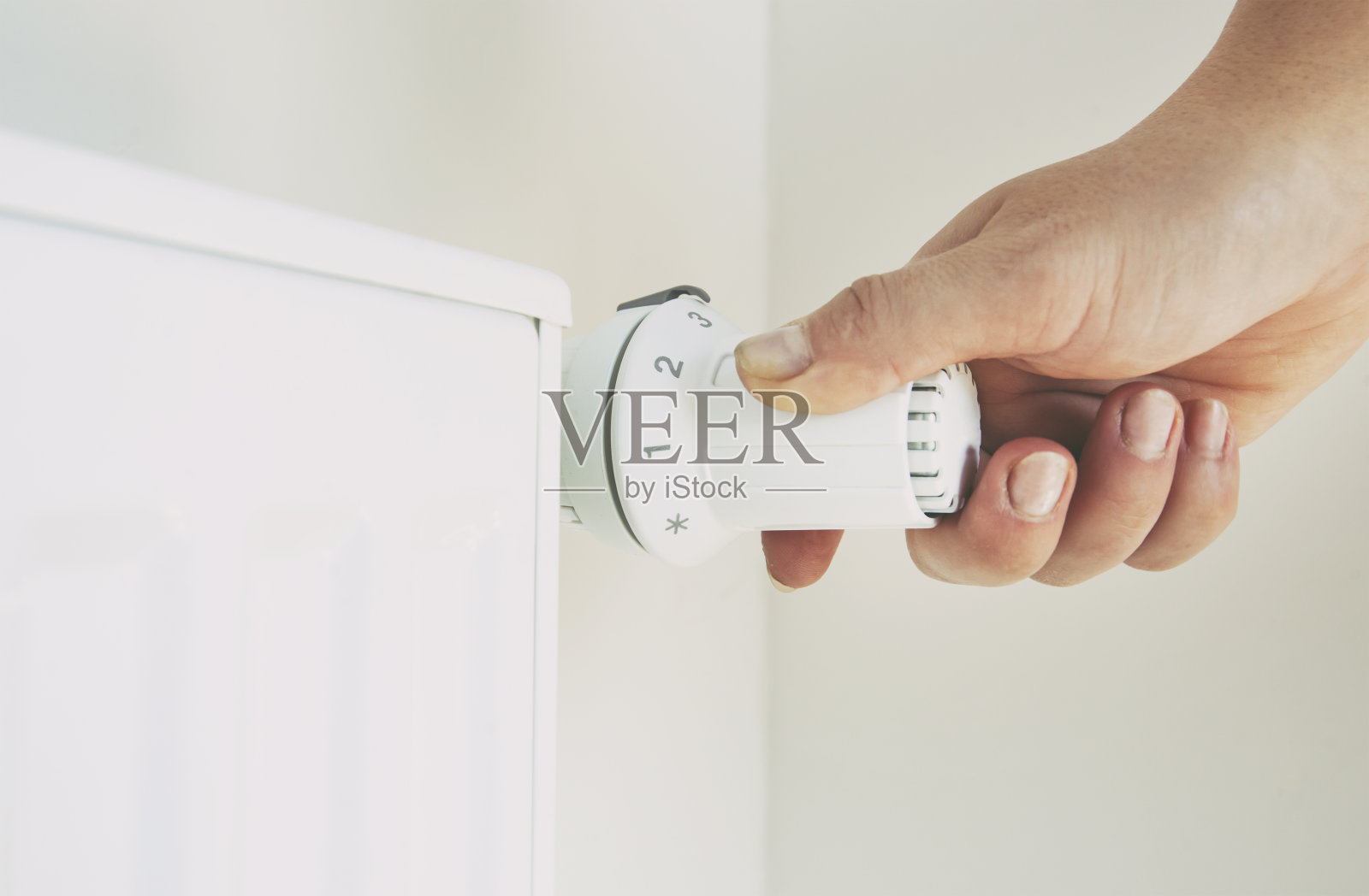 女人通过调节恒温器来提高散热器的温度照片摄影图片