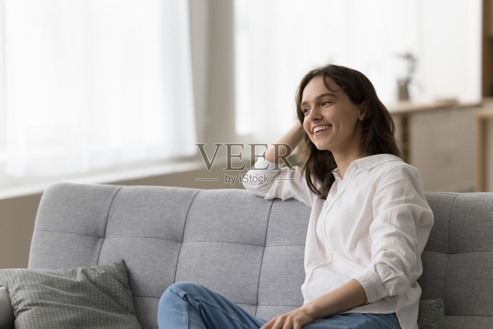 快乐的漂亮年轻女子放松在舒适的沙发上照片摄影图片