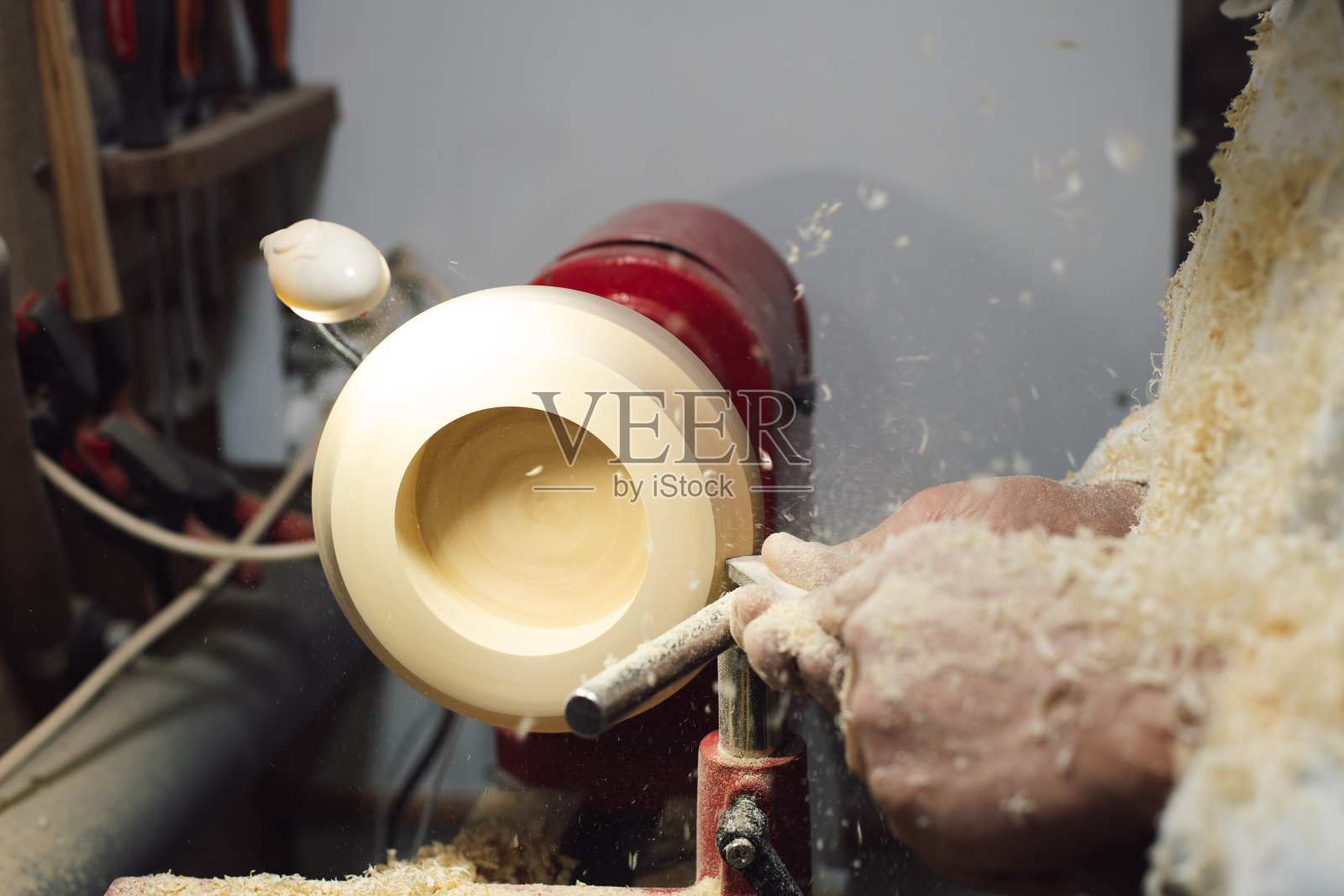 木工在车床上用木屑盖着他的手加工一块木头照片摄影图片