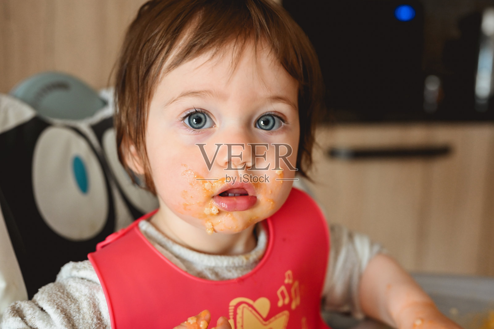 小宝宝吃着晚饭，弄得乱七八糟。照片摄影图片