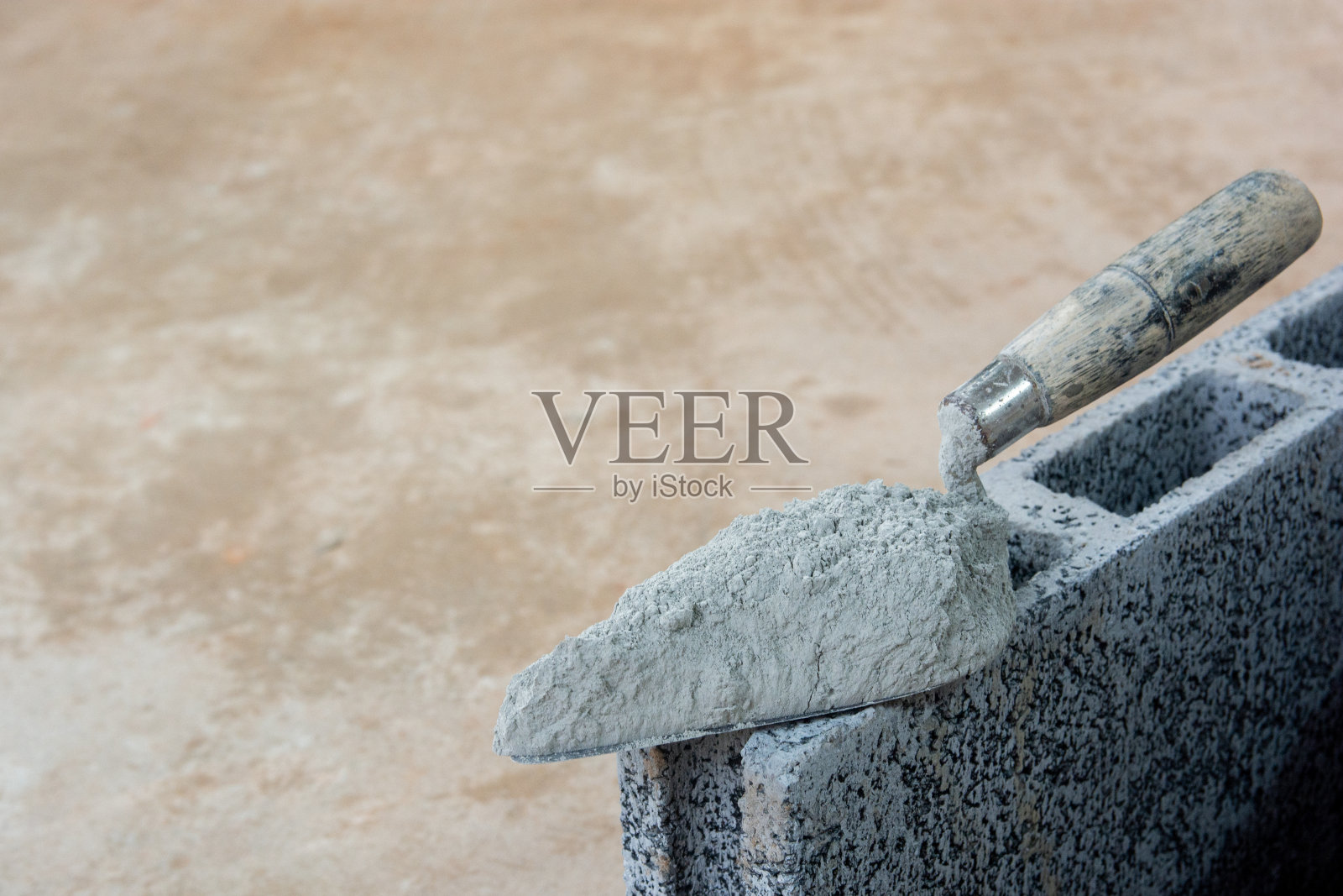 水泥粉或砂浆用泥铲抹在混凝土砖上进行施工。照片摄影图片