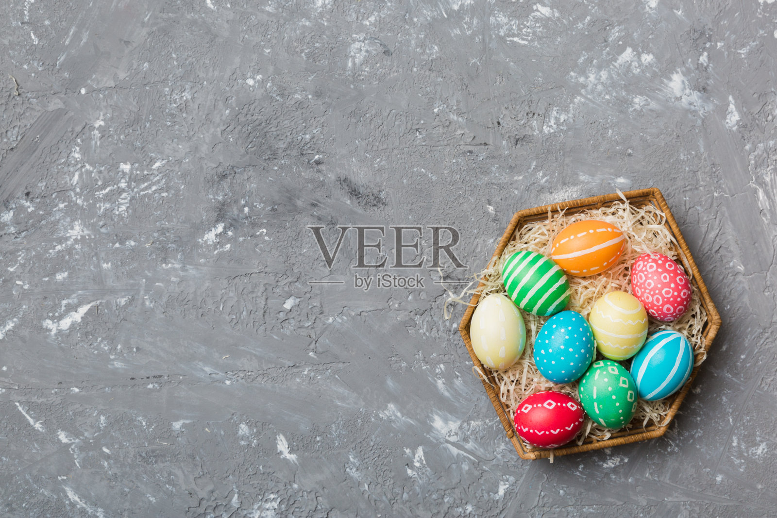 多种颜色的复活节彩蛋在编织篮子上的彩色背景。色彩柔和的彩蛋。假日概念与复制空间照片摄影图片