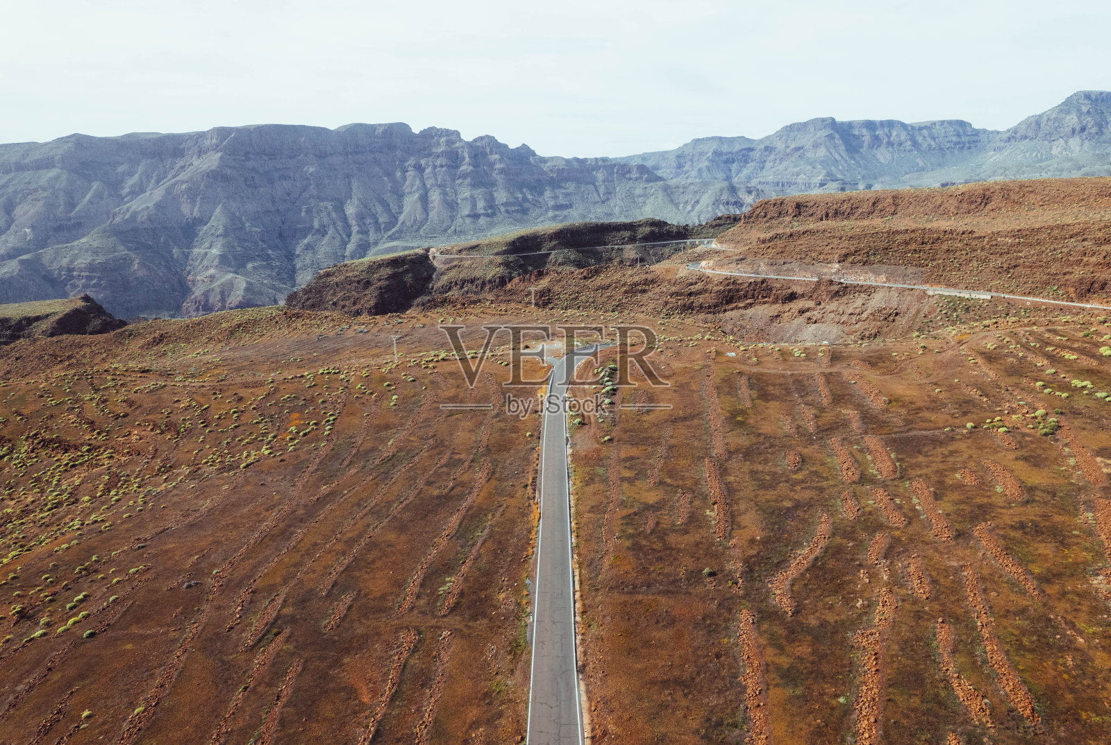 荒凉的道路在干旱的景观和山脉中间的无人机视图照片摄影图片