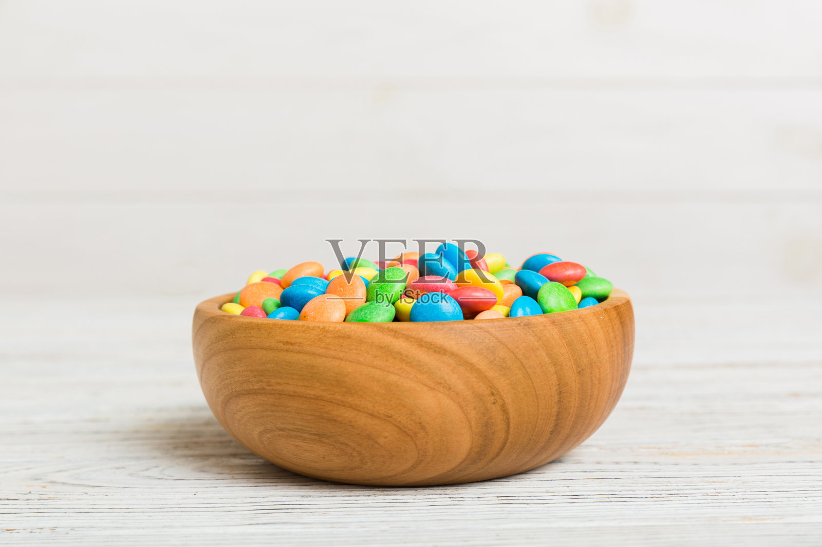 五彩缤纷的糖果放在彩色背景的碗里。生日和节日概念。带有复制空间的俯视图照片摄影图片