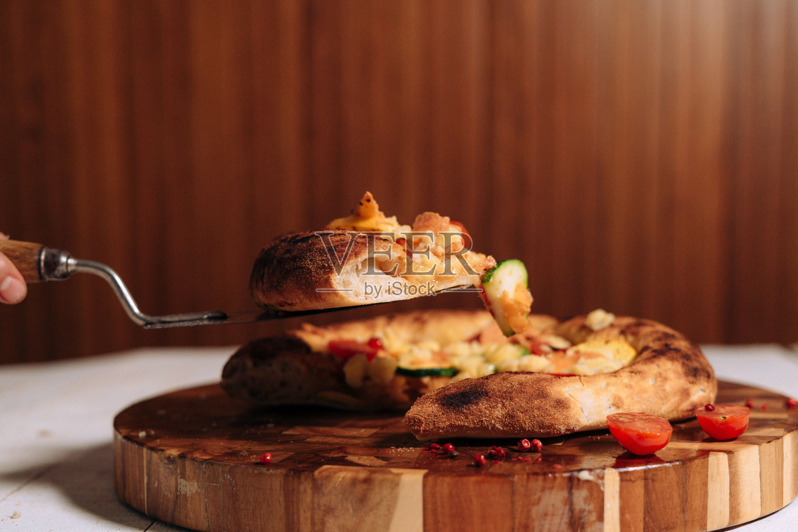 人们用锋利的刀在砧板上精致地切比萨饼照片摄影图片