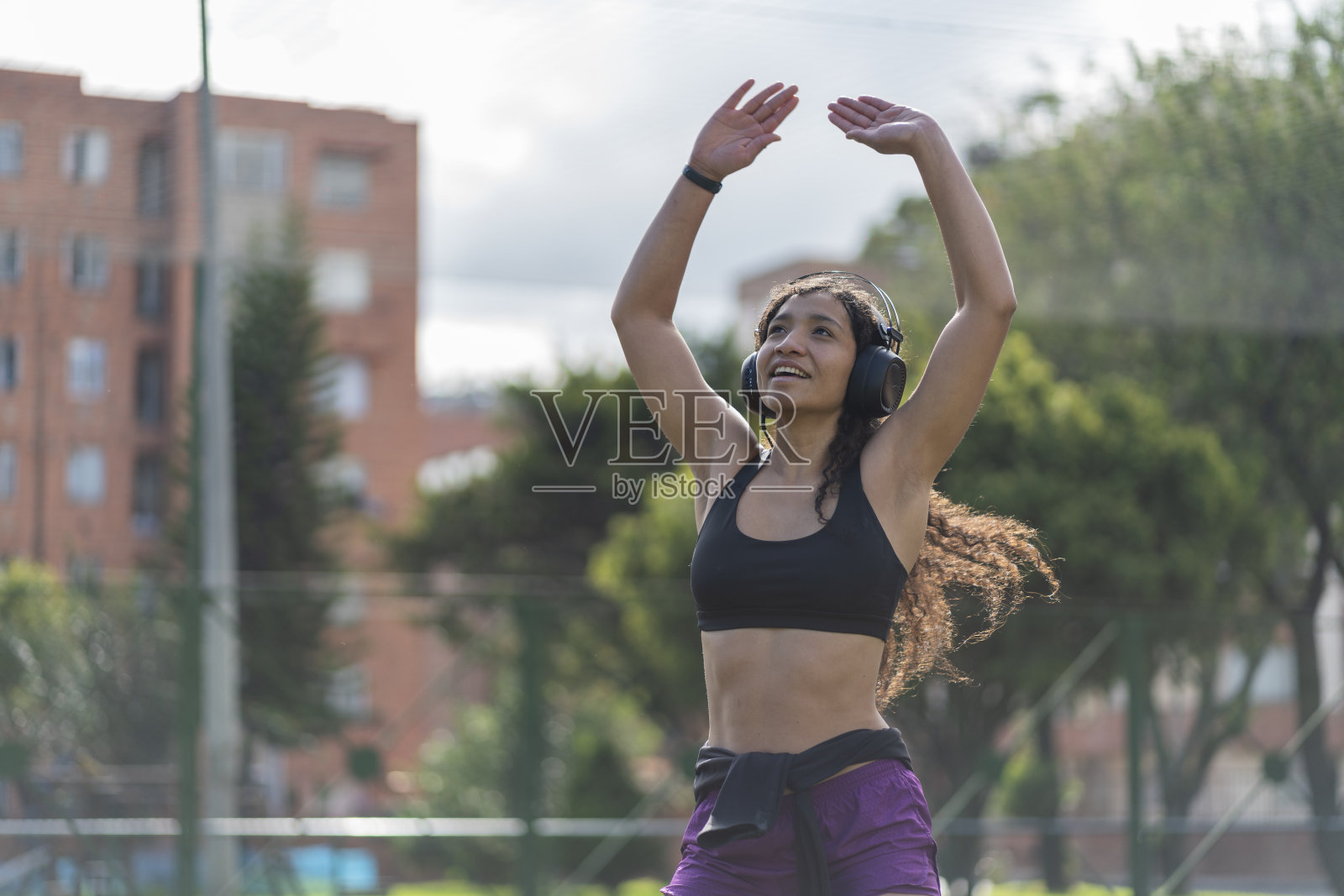 一名女子一边听音乐一边看手机，一边伸着懒腰照片摄影图片