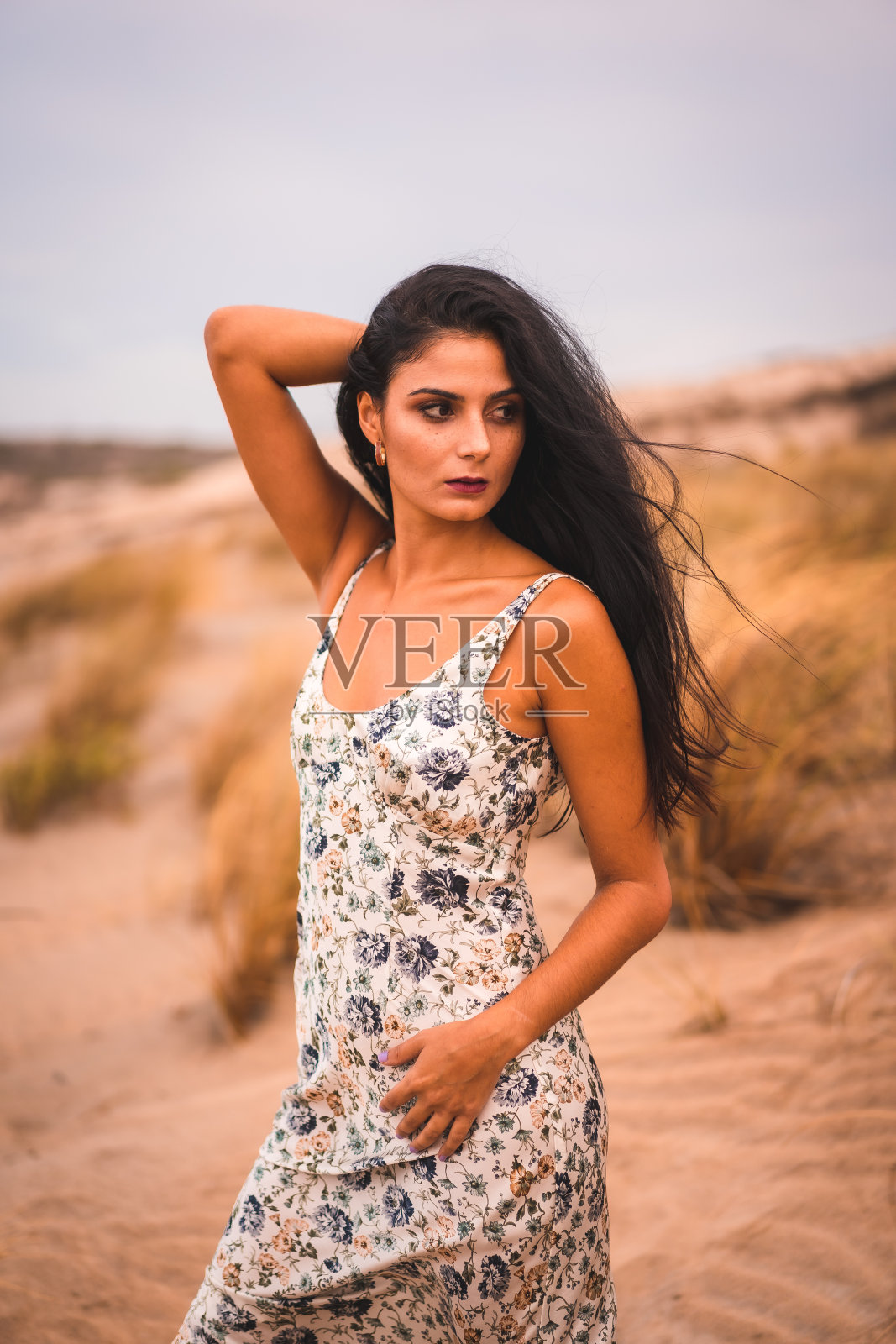 年轻的黑发白种人女子在花裙子摆姿势在卡波德加塔海滩，西班牙照片摄影图片