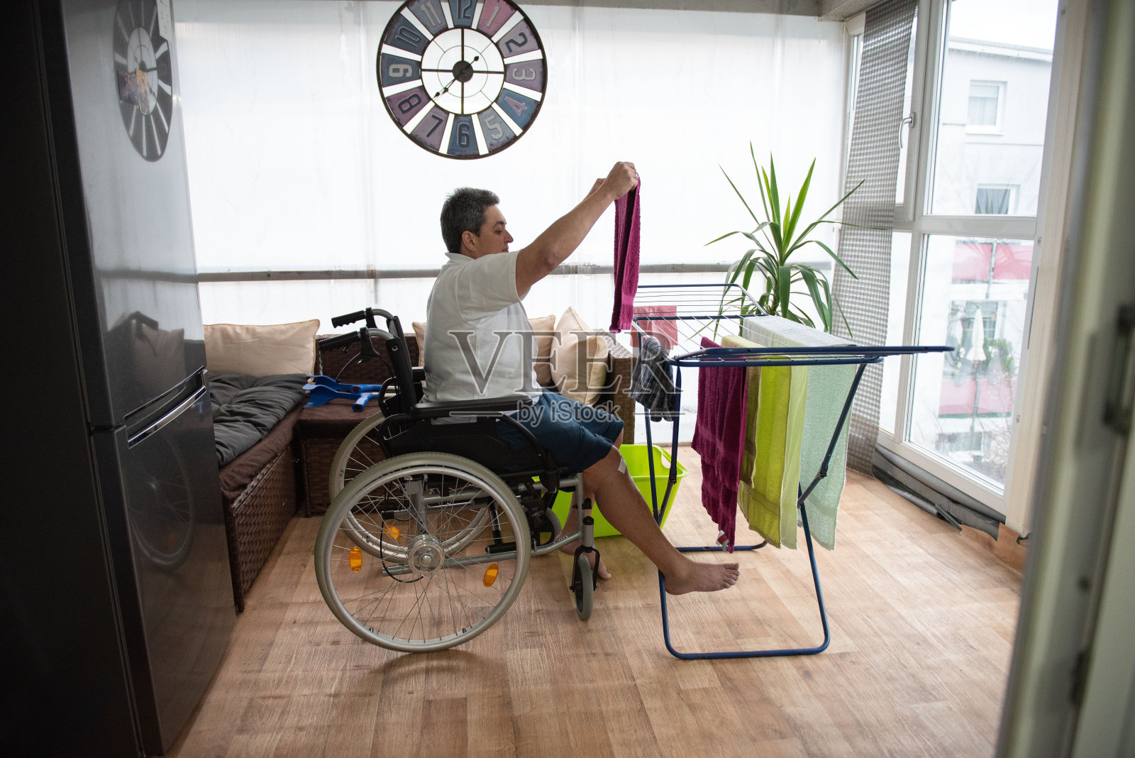 残疾人坐在轮椅上洗衣服。照片摄影图片