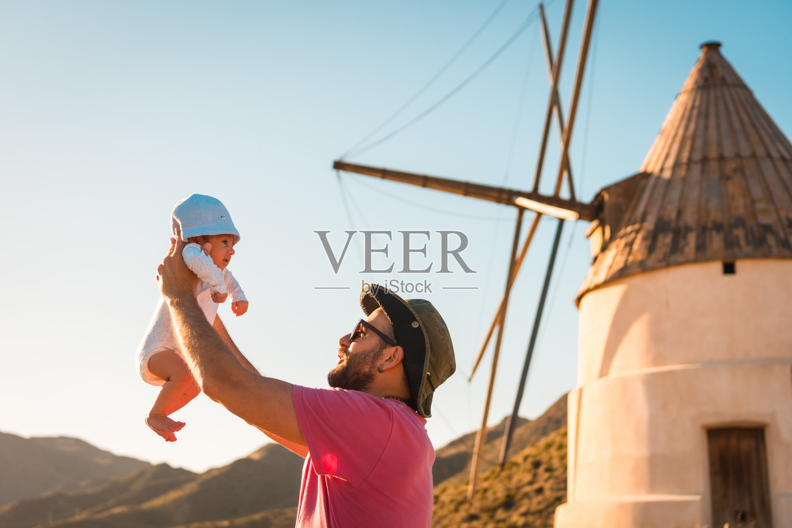 年轻的父亲和他刚出生的儿子在圣何塞度假，西班牙与磨坊的背景照片摄影图片