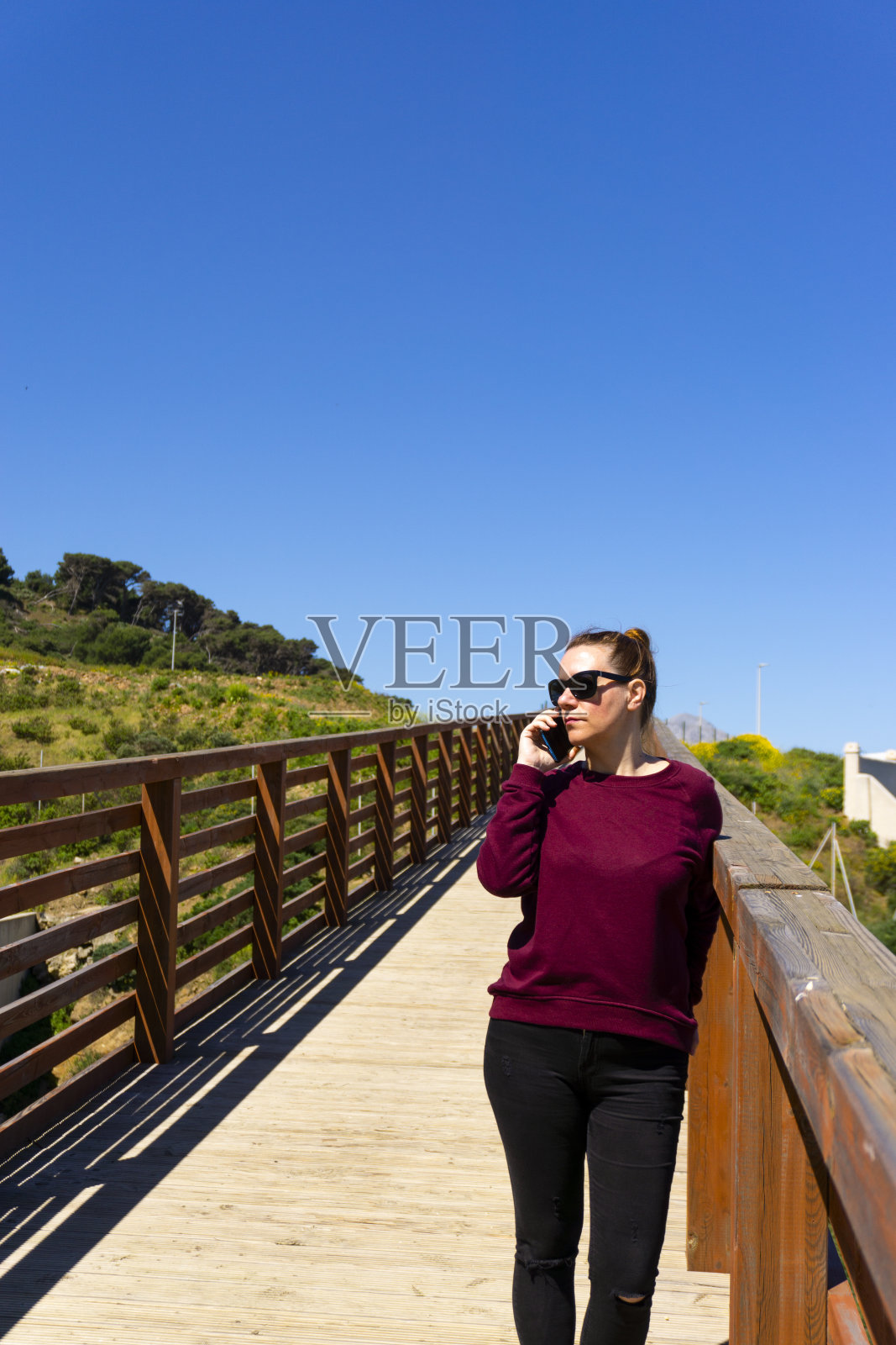 一个白人女性在阳光明媚的日子里在外面打电话的垂直镜头照片摄影图片