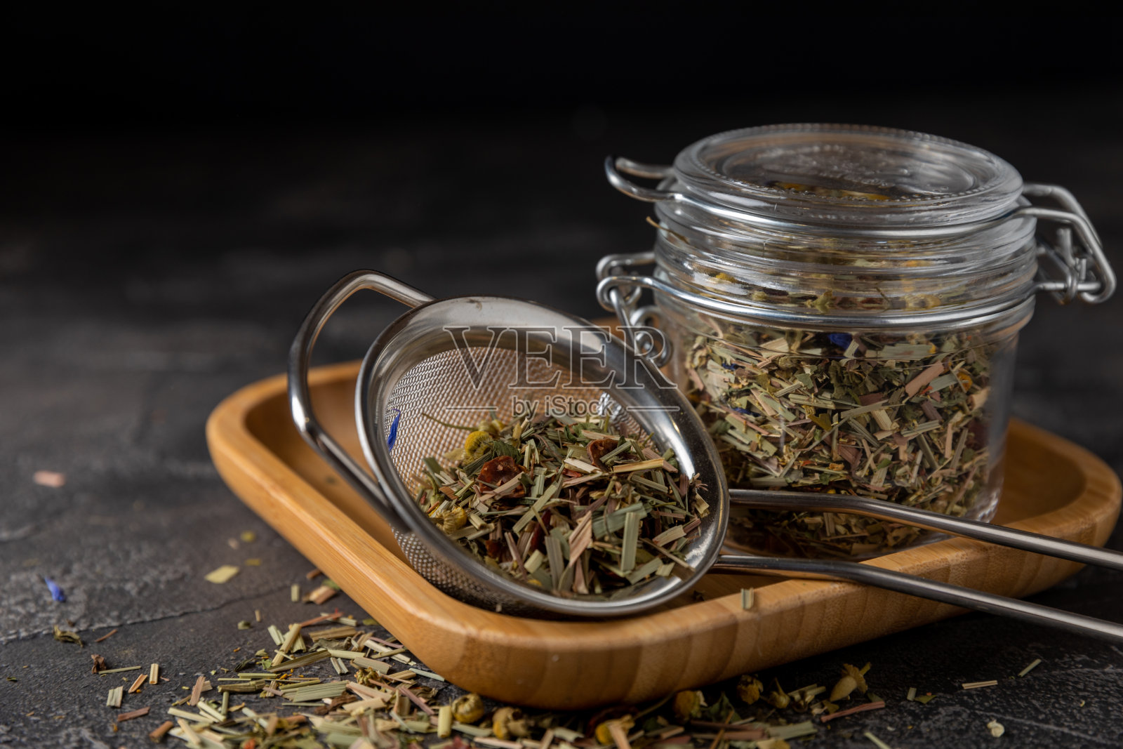 草本茶和绿色茶叶在一个透明的罐子里，茶在一个过滤器在一个黑色的大理石背景。茶的概念。前视图。副本的空间。免疫喝。照片摄影图片