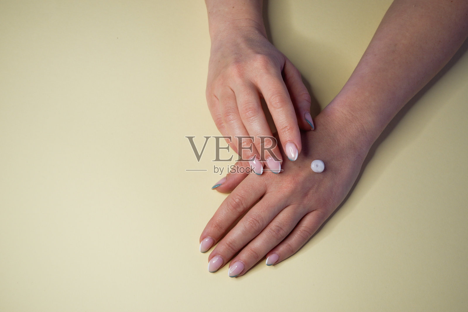 女孩在手上涂了润肤霜。手部特写，黄色背景。照片摄影图片