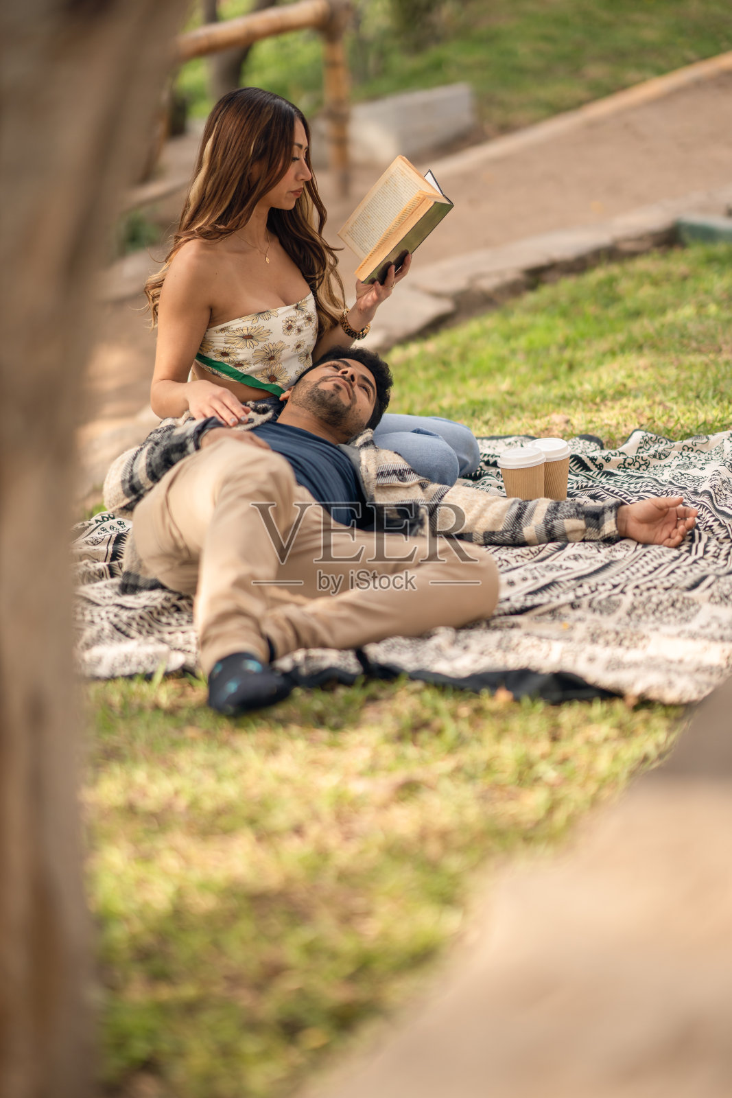 一对情侣在公园里悠闲地看书照片摄影图片