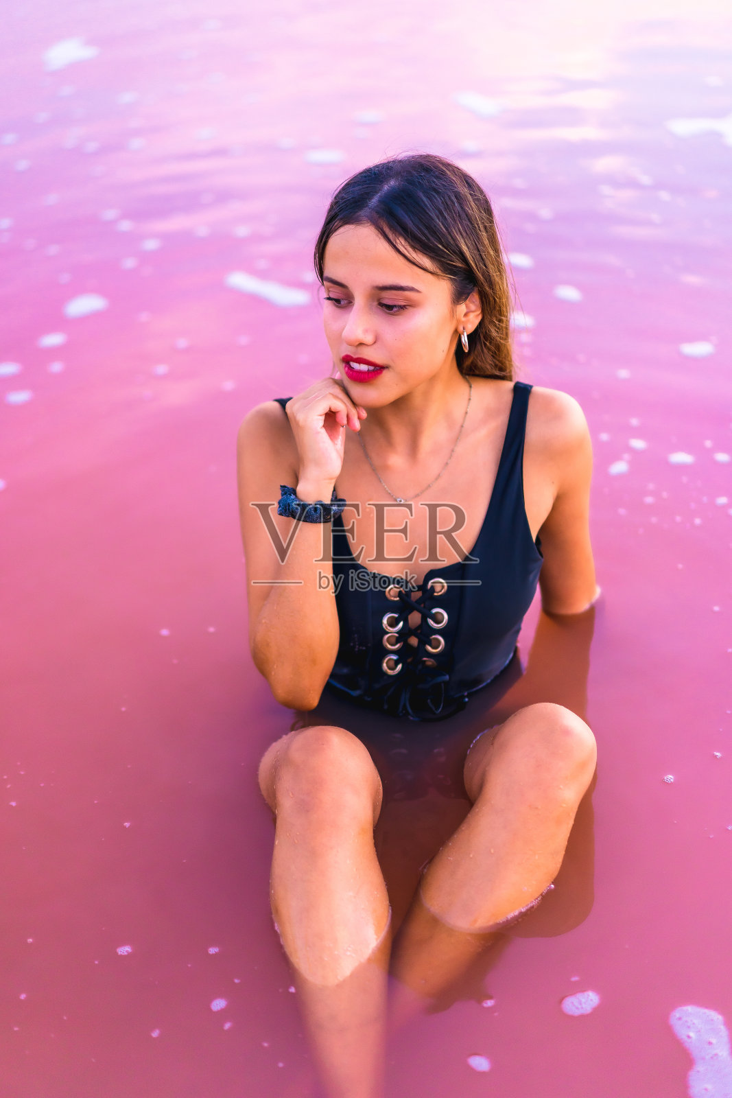 身着黑色泳装的年轻黑发女性在西班牙阿利坎特托雷维耶哈的粉红色泻湖上照片摄影图片