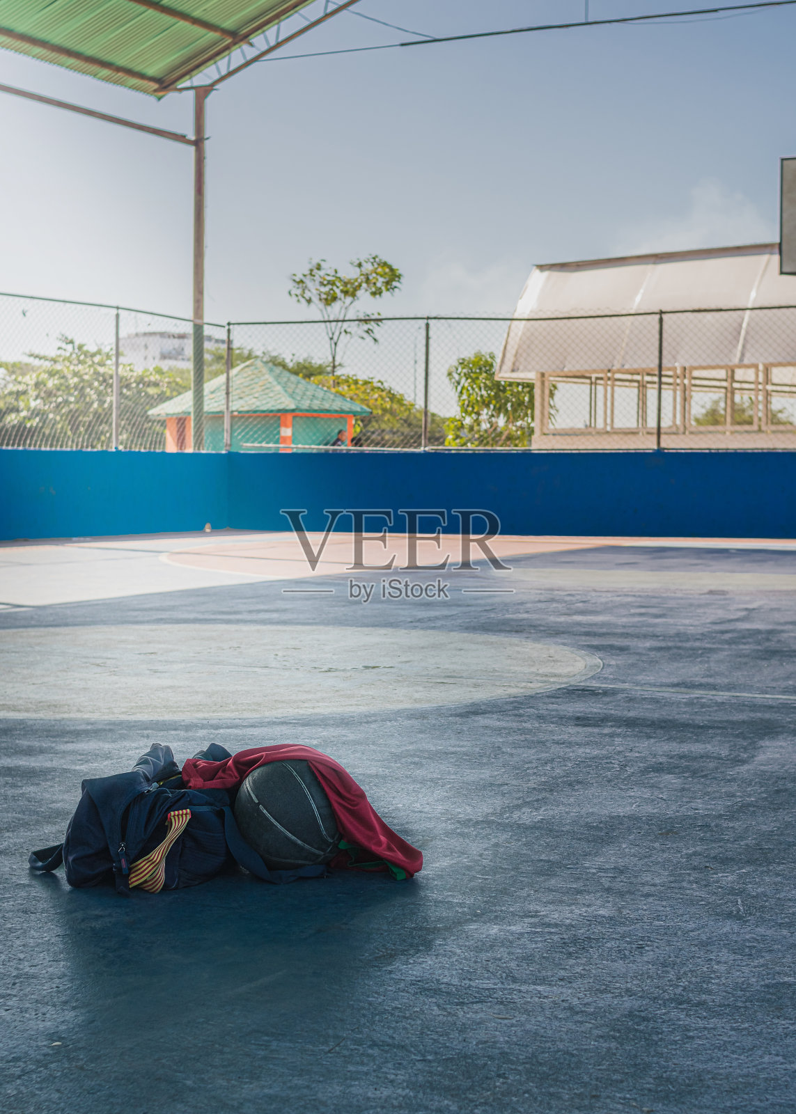 在市区一个水泥运动场的地板上，蓝色的运动包和篮球照片摄影图片