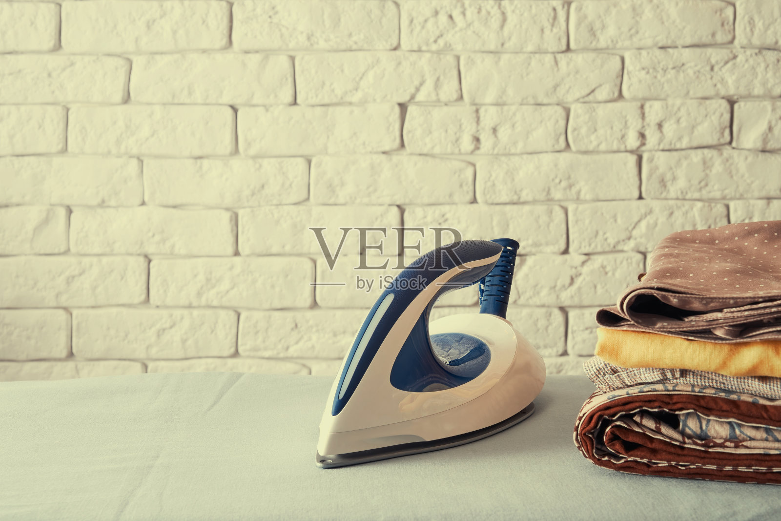 用蓝色熨斗和衣服叠在熨衣板上的色调形象照片摄影图片