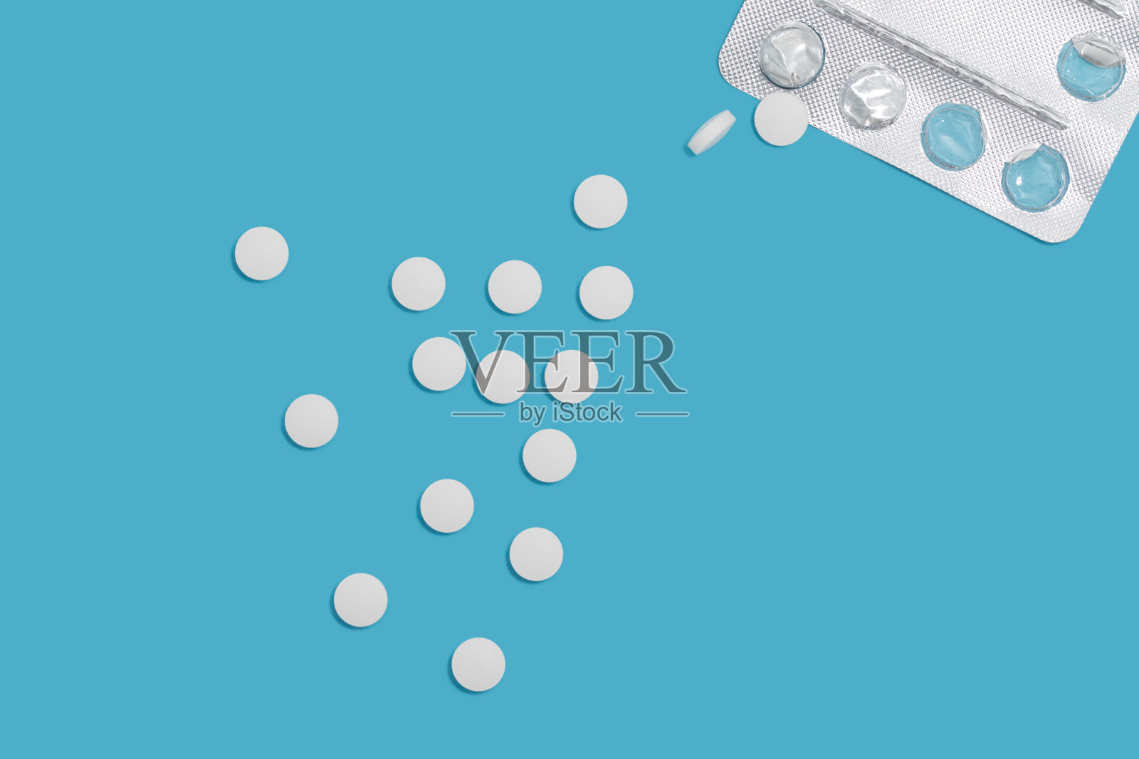 银色空药丸包装和下落药丸作为流动在蓝色背景，俯视图。医学和治疗背景——预防和治疗疾病的偏方。照片摄影图片