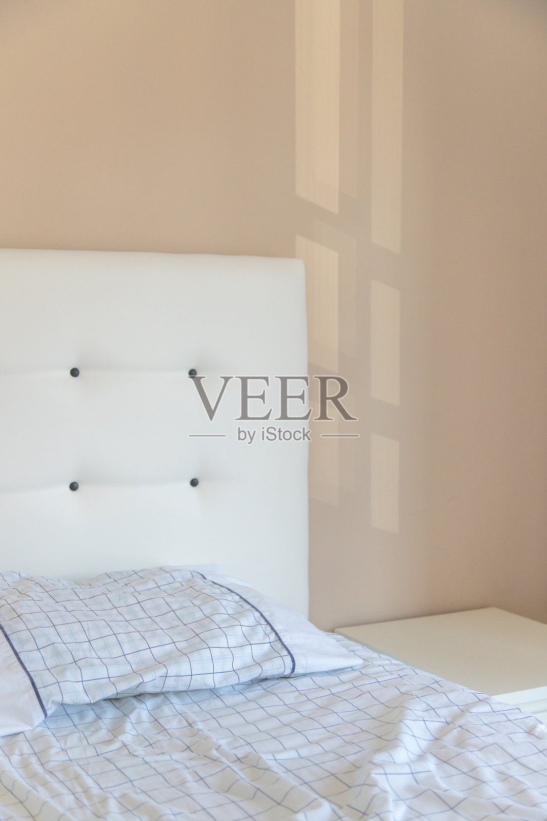 明亮的卧室内部细节，有枕头和床头板，非常舒适，舒适和现代，光线穿过墙壁。白色和柔和的色调。本空间照片摄影图片