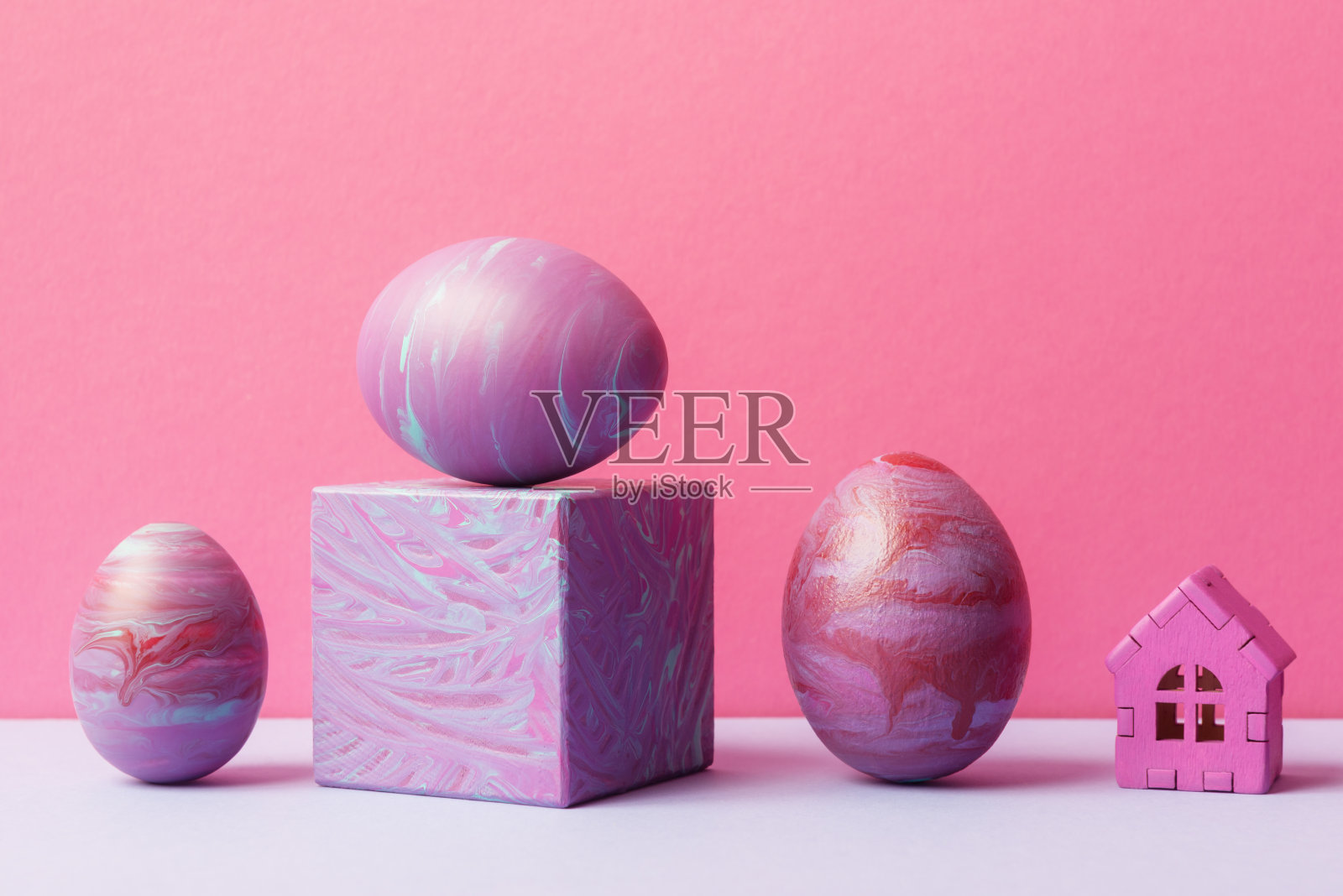 装饰复活节彩蛋画在流体艺术技术和玩具房子在粉红色的背景。复活节节日问候概念照片摄影图片