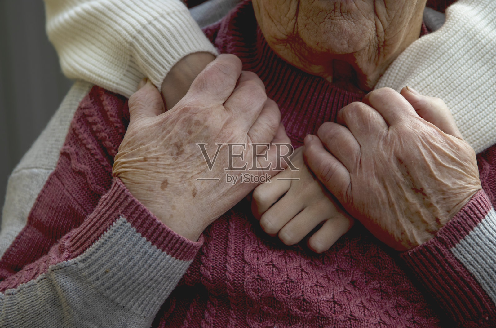 一位老人和一位年轻妇女的手相互拥抱在一起。关爱老一辈，尊重老人照片摄影图片