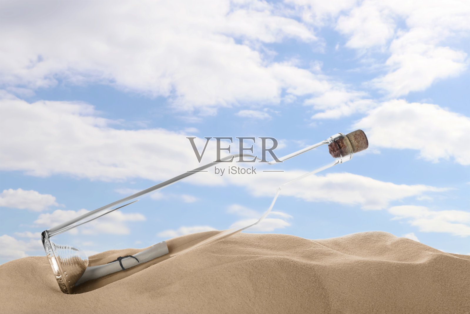 用软木塞堵住的玻璃瓶，上面有纸卷，放在沙滩上照片摄影图片