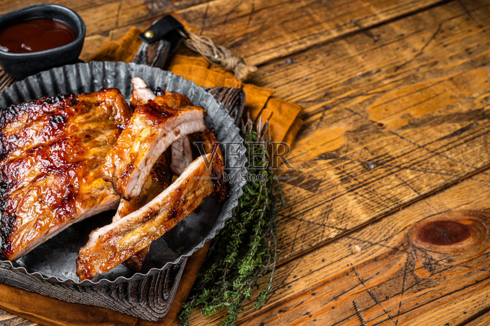 烟熏排骨上了烧烤酱汁，装在钢板里。木制背景。前视图。本空间照片摄影图片