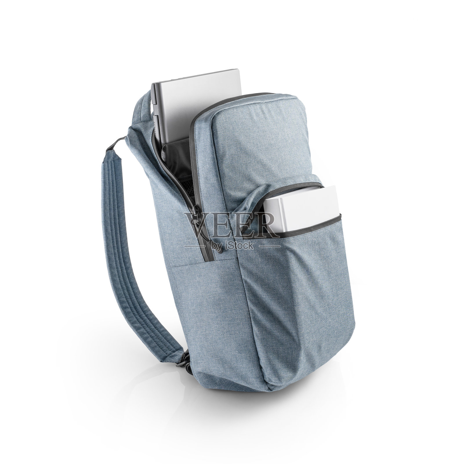 蓝色背包，笔记本电脑和一本书在开放的口袋或隔间。照片摄影图片