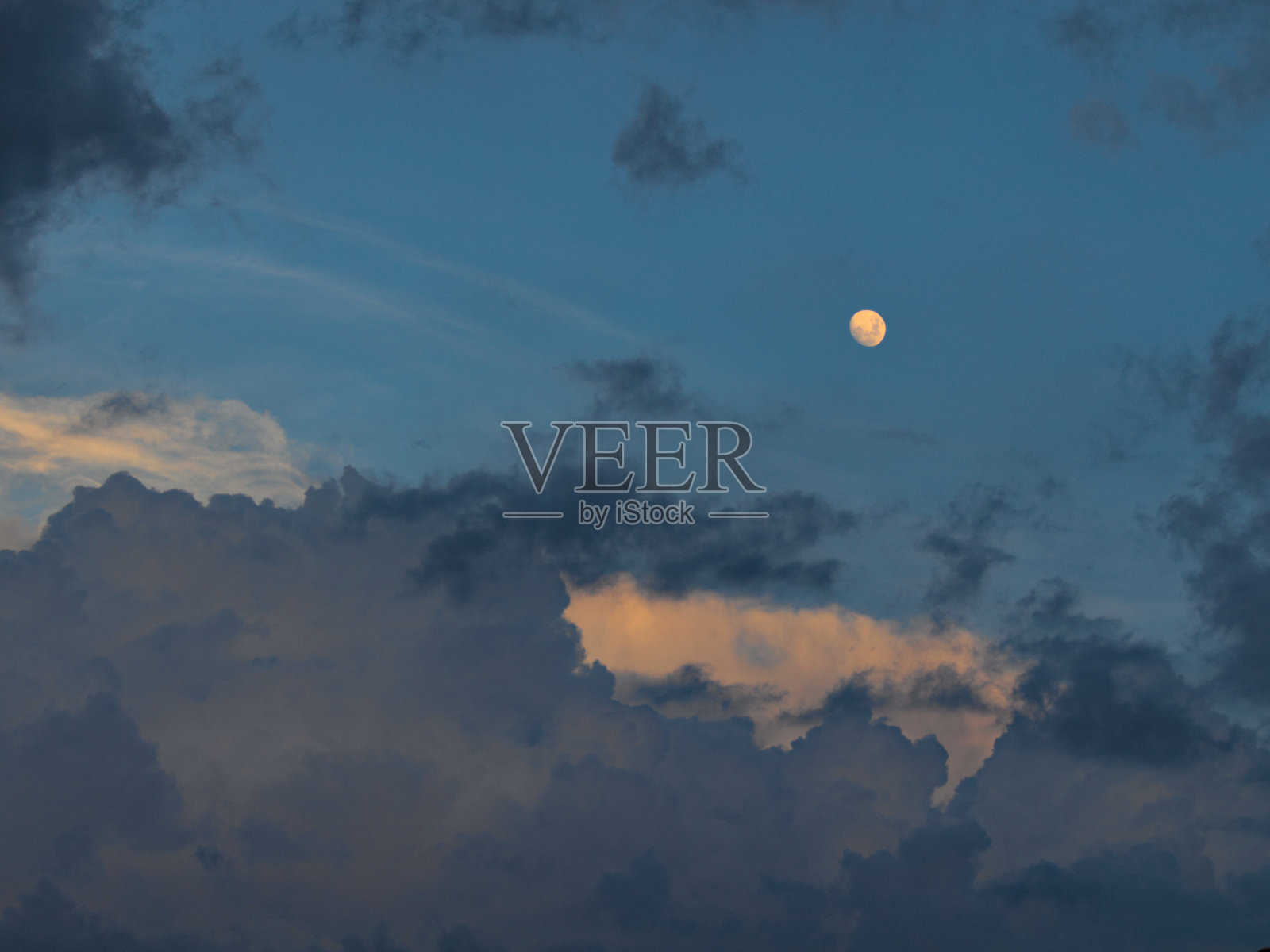 在卡普里岛蓝色的天空下，一个凸月的景观图像，地平线上的阴影云和黑色的云缕在黄昏中漂移照片摄影图片