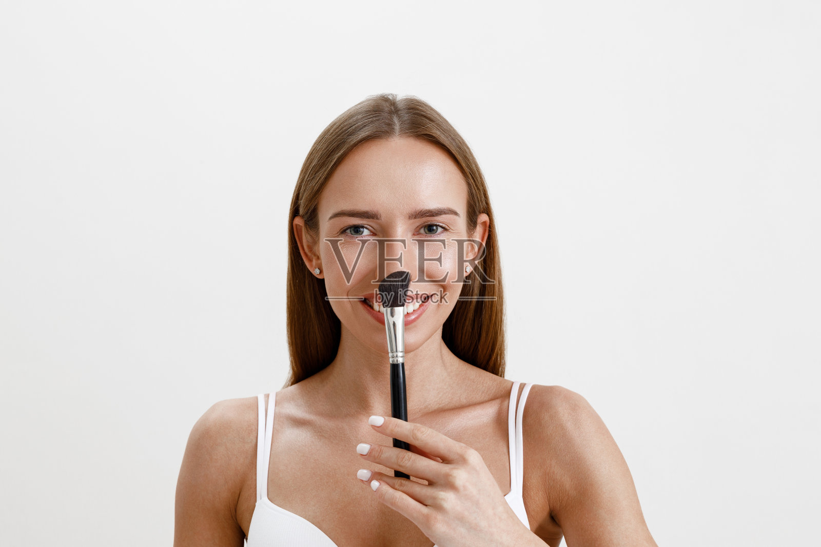 皮肤健康的微笑女性将大化妆刷放在脸的正中央照片摄影图片