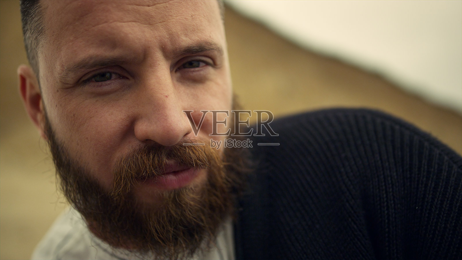 大胡子男人看着相机。严肃的家伙脸休息在海滩自然景观。照片摄影图片