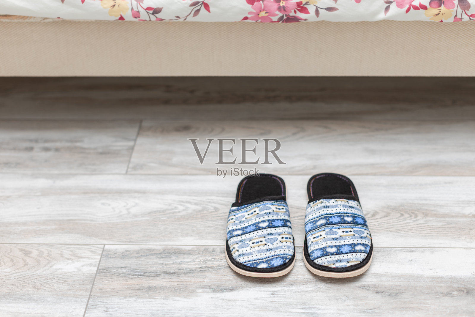 拖鞋在人睡觉的床旁边。照片摄影图片